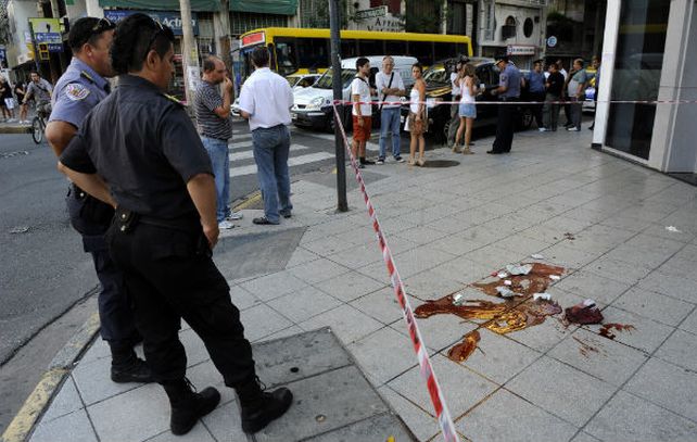 Dos policías observan azorados la sangre y los restos de masa encefálica en la vereda donde mataron de un balazo a Maximiliano Rodríguez. (Foto: H.Río.)