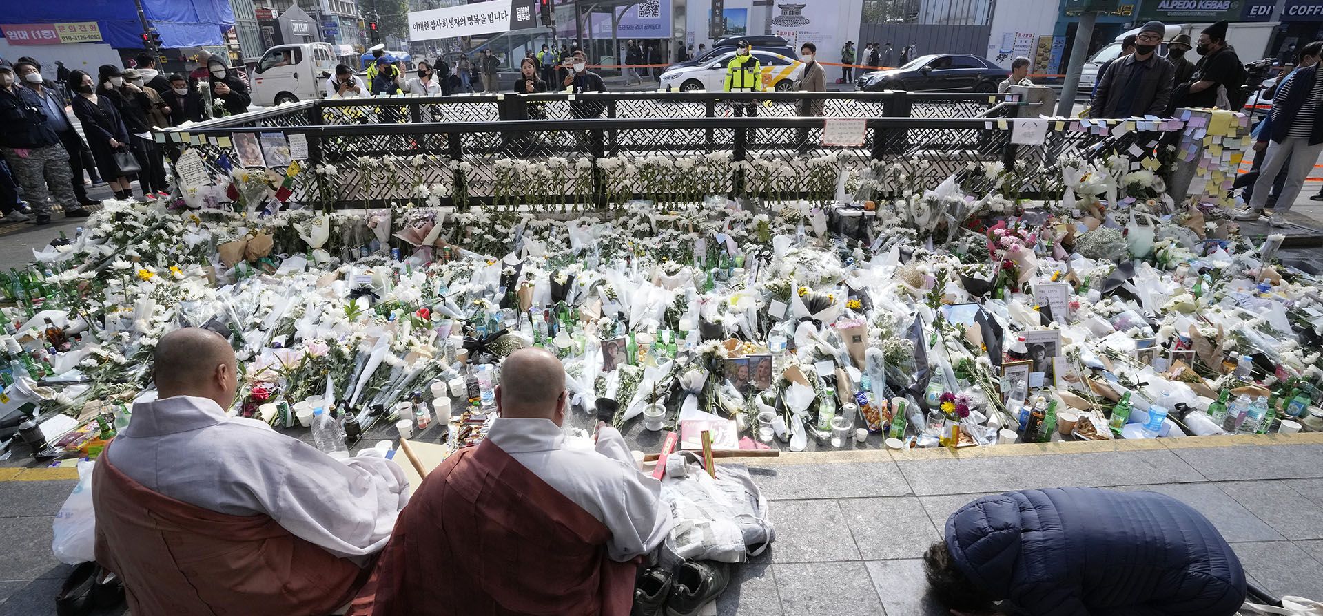 Monjes budistas rezan por las víctimas de un accidente mortal después de las festividades de Halloween del sábado por la noche en una calle cercana al lugar del accidente en Seúl, Corea del Sur, el martes 1 de noviembre de 2022.