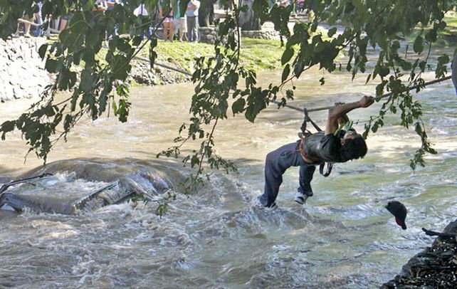 Un rescatista inicia las acciones para retirar un auto de las aguas de un arroyo en la ciudad de Villa Allende