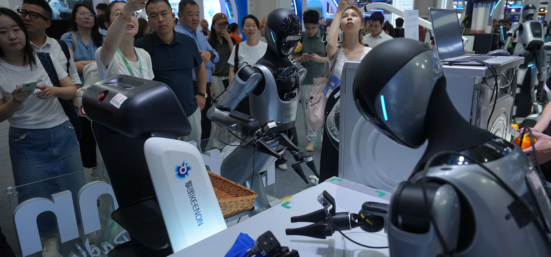 Visitantes observan un robot realizando tareas domésticas en un stand durante la Conferencia Mundial de Robótica en el Centro Internacional de Convenciones y Exposiciones Beiren Yichuang en Pekín, el miércoles 19 de agosto de 2026. (Foto AP/Andy Wong)