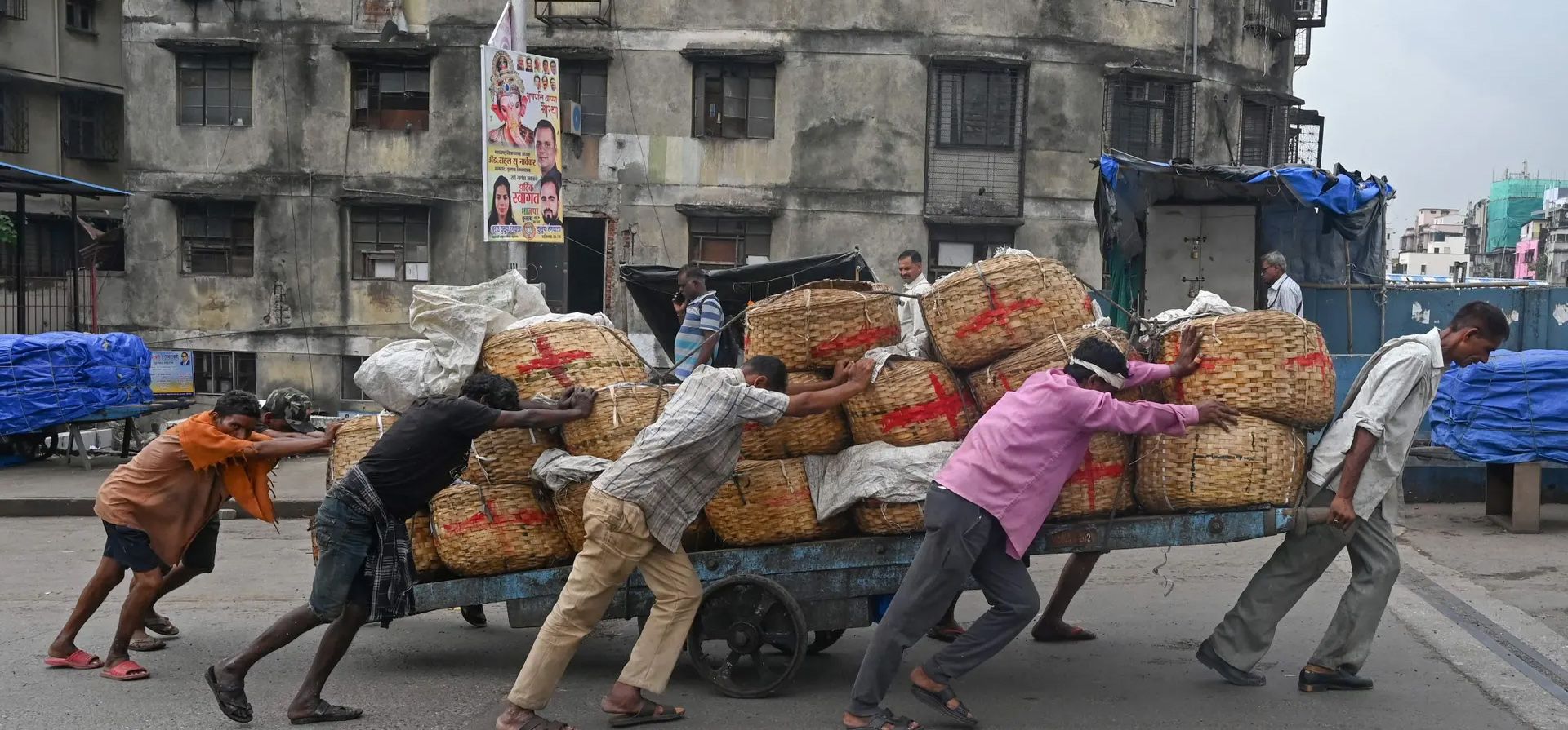 Trabajadores empujan un carro de mano cargado con cestas de pescado, Bombay, India. Fotografía: Indranil Mukherjee/AFP/Getty Images