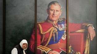 Un hombre camina frente a un retrato de Carlos III en la vía pública del centro de Londres.