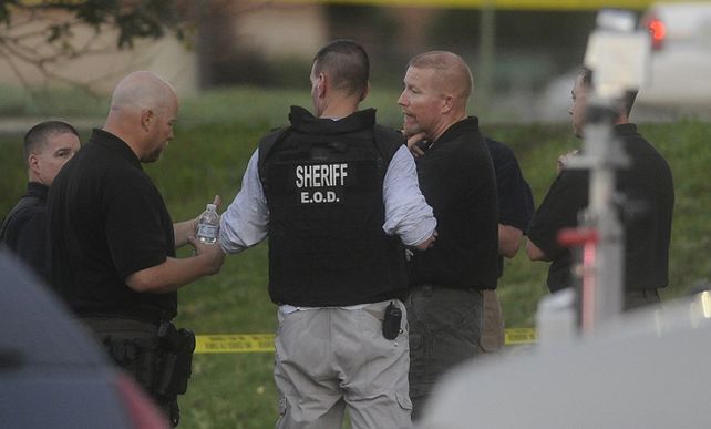 Un herido es atendido por las fuerzas de seguridad fuera del cine. (Foto: AP)