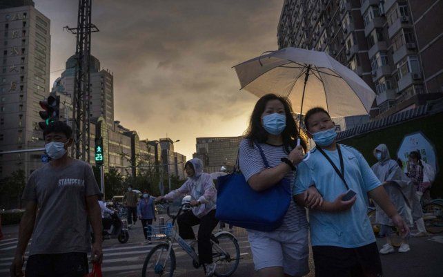 Personas cruzan una intersección durante la hora pico de la tarde en Beijing, el jueves 26 de agosto de 2021. La lucha por un aire más limpio es una victoria poco común para la disidencia pública.