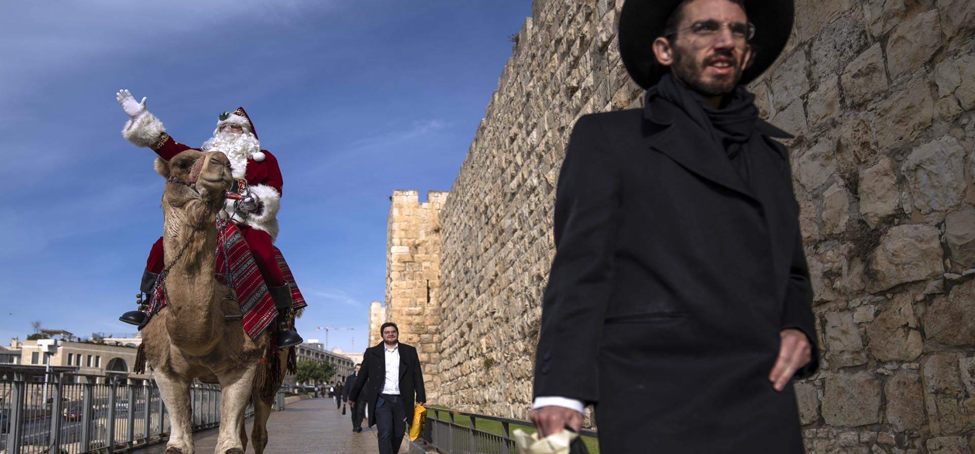 Un hombre vestido como Papá Noel montado en un camello realiza una gira por fuera de las murallas de la Ciudad Vieja de Jerusalén, antes de las próximas vacaciones de Navidad, el jueves 23 de diciembre de 2021. Foto: AP