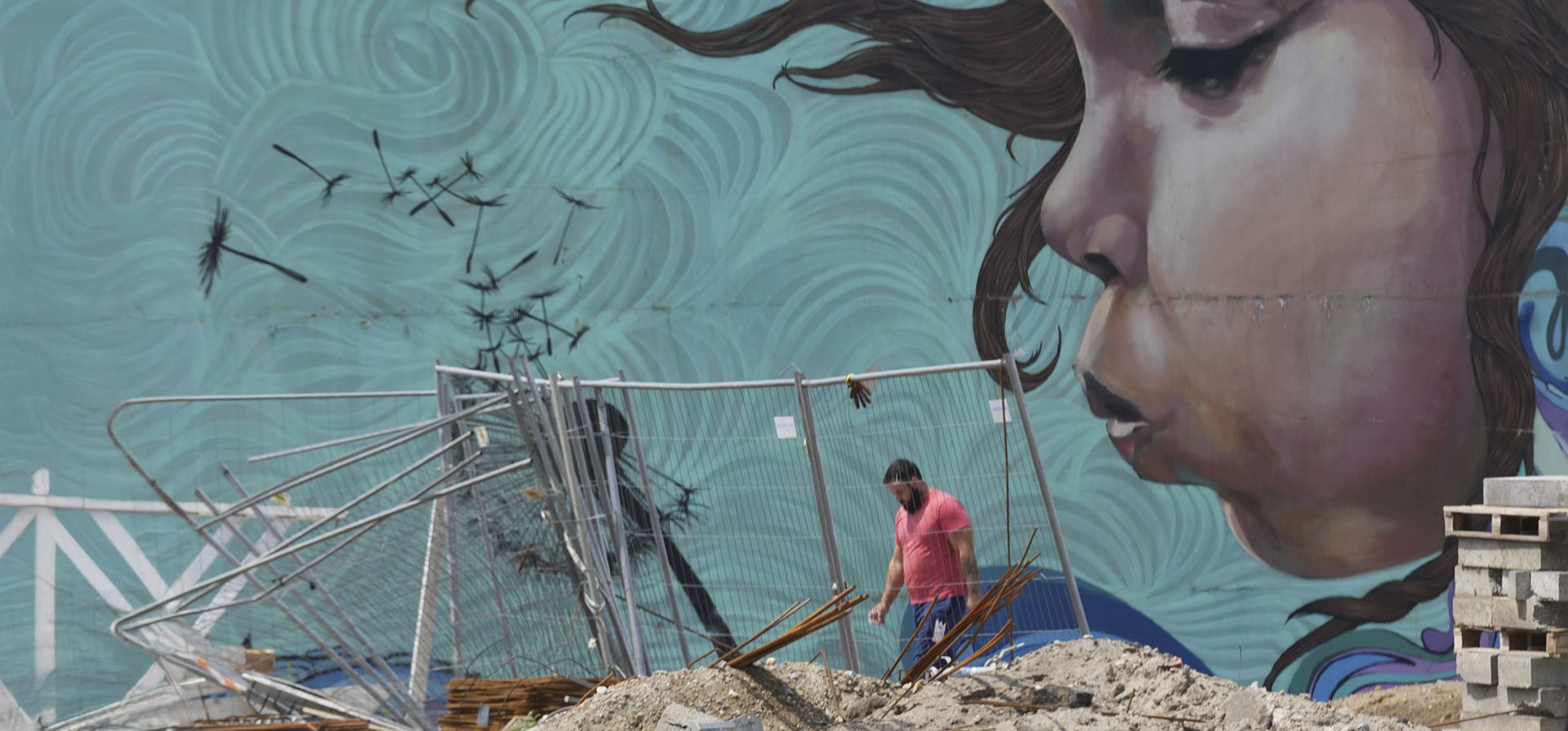 Un trabajador pasa junto a un grafiti en el pilono del desmantelado Un trabajador pasa junto a un grafiti en el pilono del desmantelado