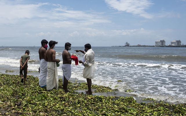 Un grupo de&nbsp; jóvenes realizan los últimos ritos por su madre fallecida en la costa del Mar Arábigo en Kochi