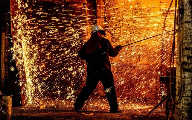 Un trabajador del horno limpia los restos de fundición del horno en Hargreaves Foundry