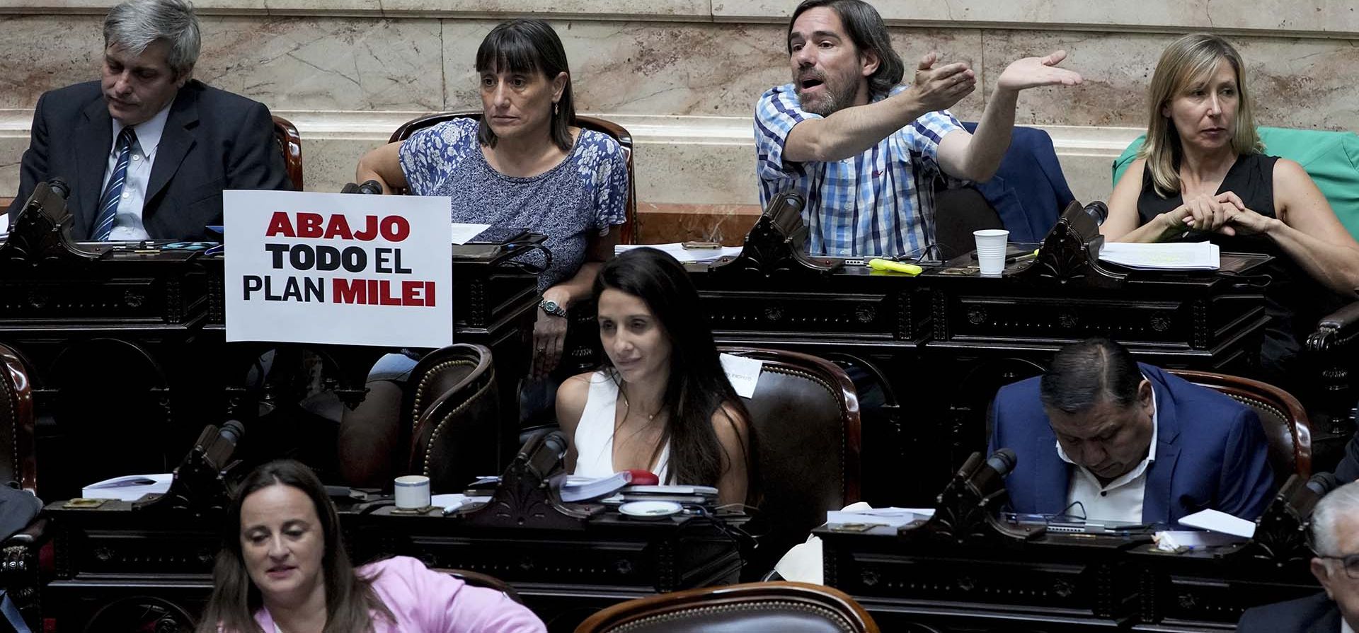 Un cartel que dice en español "Abajo todo el plan de Milei" cuelga junto a legisladores de la oposición antes del inicio de un debate sobre un proyecto de ley promovido por el presidente argentino Javier Milei, en el Congreso en Buenos Aires, Argentina, el miércoles 31 de enero de 2024. (Foto AP/Natacha Pisarenko) Un cartel que dice en español "Abajo todo el plan de Milei" cuelga junto a legisladores de la oposición antes del inicio de un debate sobre un proyecto de ley promovido por el presidente argentino Javier Milei, en el Congreso en Buenos Aires, Argentina, el miércoles 31 de enero de 2024. (Foto AP/Natacha Pisarenko)