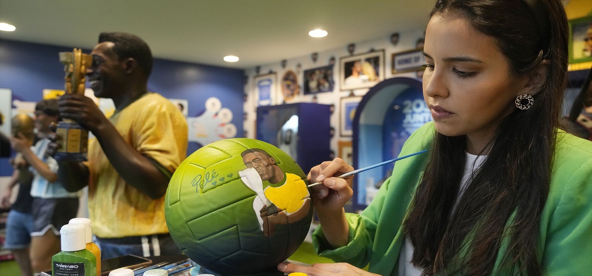 La artista paraguaya Lili Cantero pinta un balón con el rostro de la leyenda del fútbol brasileño Pelé, en la sede de la Conmebol en Doha, Qatar, el miércoles 7 de diciembre de 2022. (Foto AP/Jorge Sáenz)