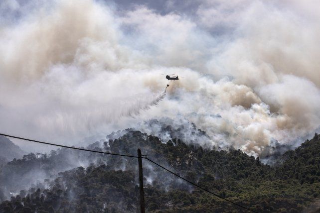Un helicóptero militar arroja agua sobre un bosque cerca del pueblo de Schinos, Corinto, Grecia. Un gran incendio forestal al oeste de Atenas dañó casas y provocó evacuaciones masivas.