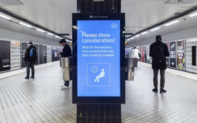 Un letrero que dice "¡Por favor, muestre consideración!" pide a los pasajeros que esperen el próximo autobús o tren si el que llega está abarrotado, en la estación central de metro en Estocolmo, Suecia.