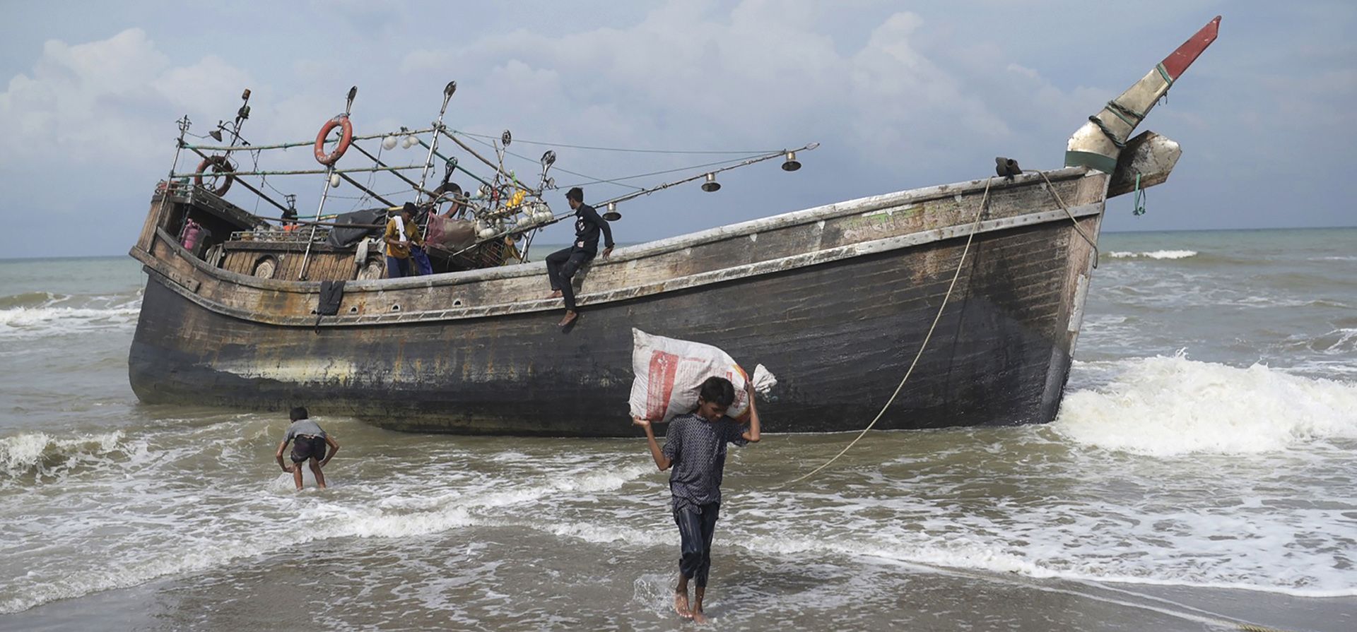 Los rohingyas étnicos recogen sus pertenencias de su bote después de anclar en la playa de Lampanah Leungah en Aceh Besar, Indonesia, el jueves 16 de febrero de 2023. Un bote que transportaba a decenas de musulmanes rohingya que huían de los campos de refugiados en Bangladesh llegó el jueves en la provincia de Aceh, dijeron funcionarios locales. (Foto AP/Riska Munawarah)