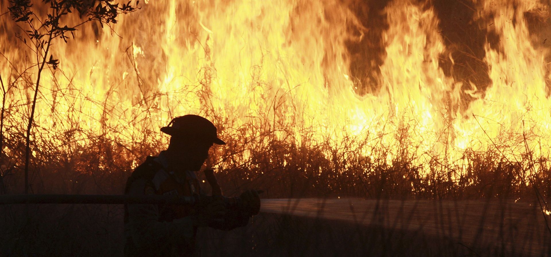 Un agente de policía arroja agua en un intento de sofocar un incendio que arrasa un campo en Ogan Ilir, en Sumatra del Sur, Indonesia, el 20 de julio de 2025. (AP Foto/Muhammad Hatta) Un agente de policía arroja agua en un intento de sofocar un incendio que arrasa un campo en Ogan Ilir, en Sumatra del Sur, Indonesia, el 20 de julio de 2025. (AP Foto/Muhammad Hatta)