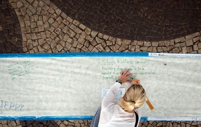Una manifestante escribe en una pancarta de 150 metros de largo instalada sobre las veredas de Copacabana.