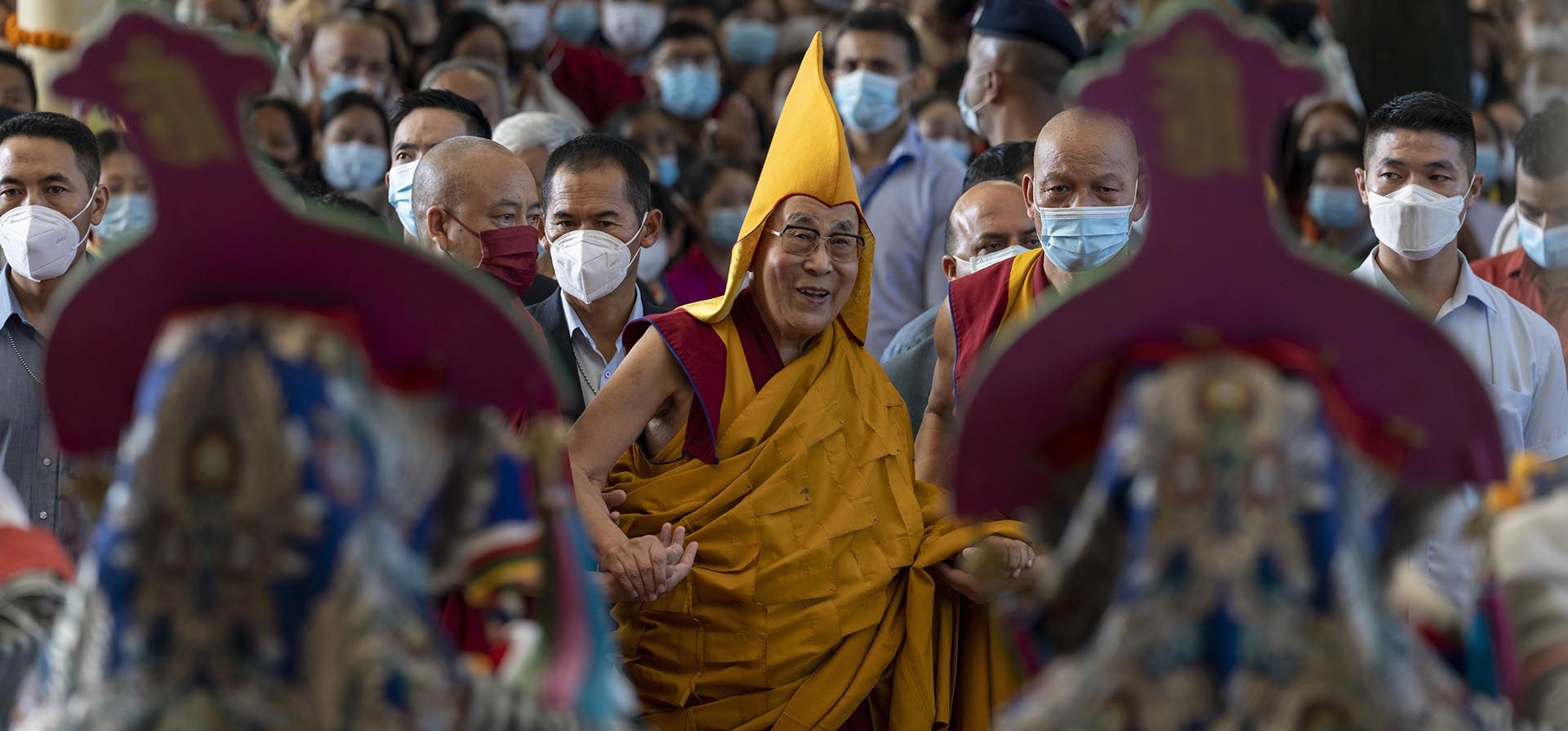 El líder espiritual tibetano, el Dalai Lama, con un sombrero ceremonial amarillo, observa una danza de bienvenida realizada por artistas tibetanos, cuando llega al templo Tsuglakhang en Dharmsala, India, el miércoles 7 de septiembre de 2022.