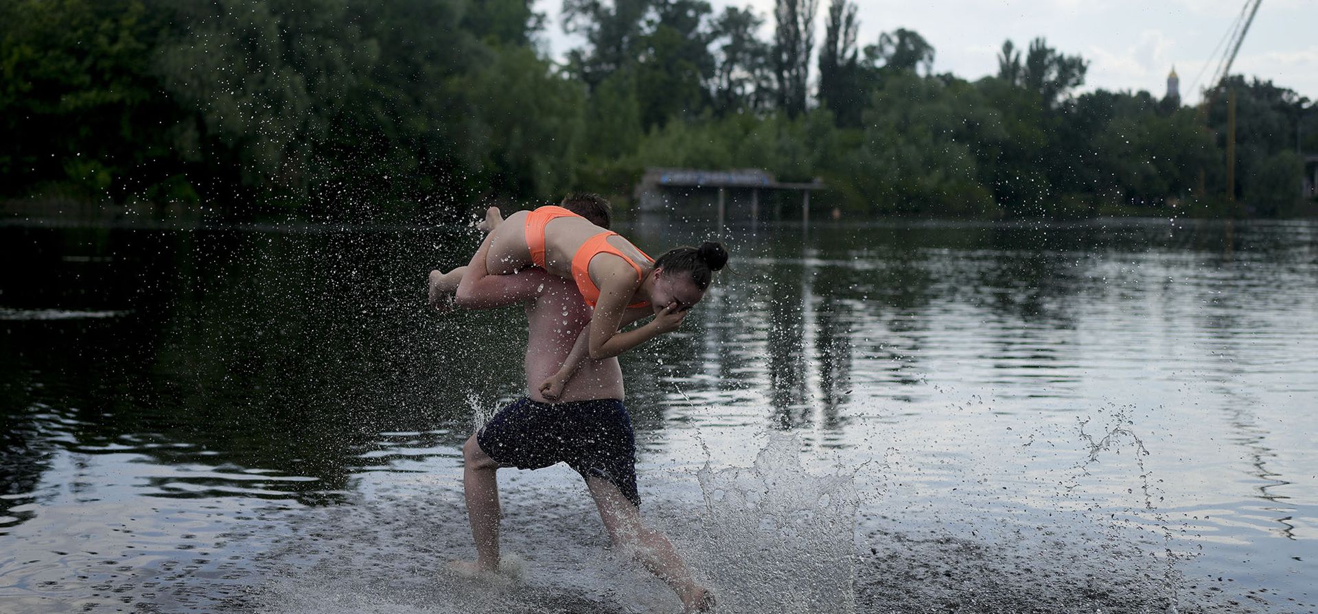 Un amigo carga a Valeria mientras corre por el río Dniéper en Kyiv.