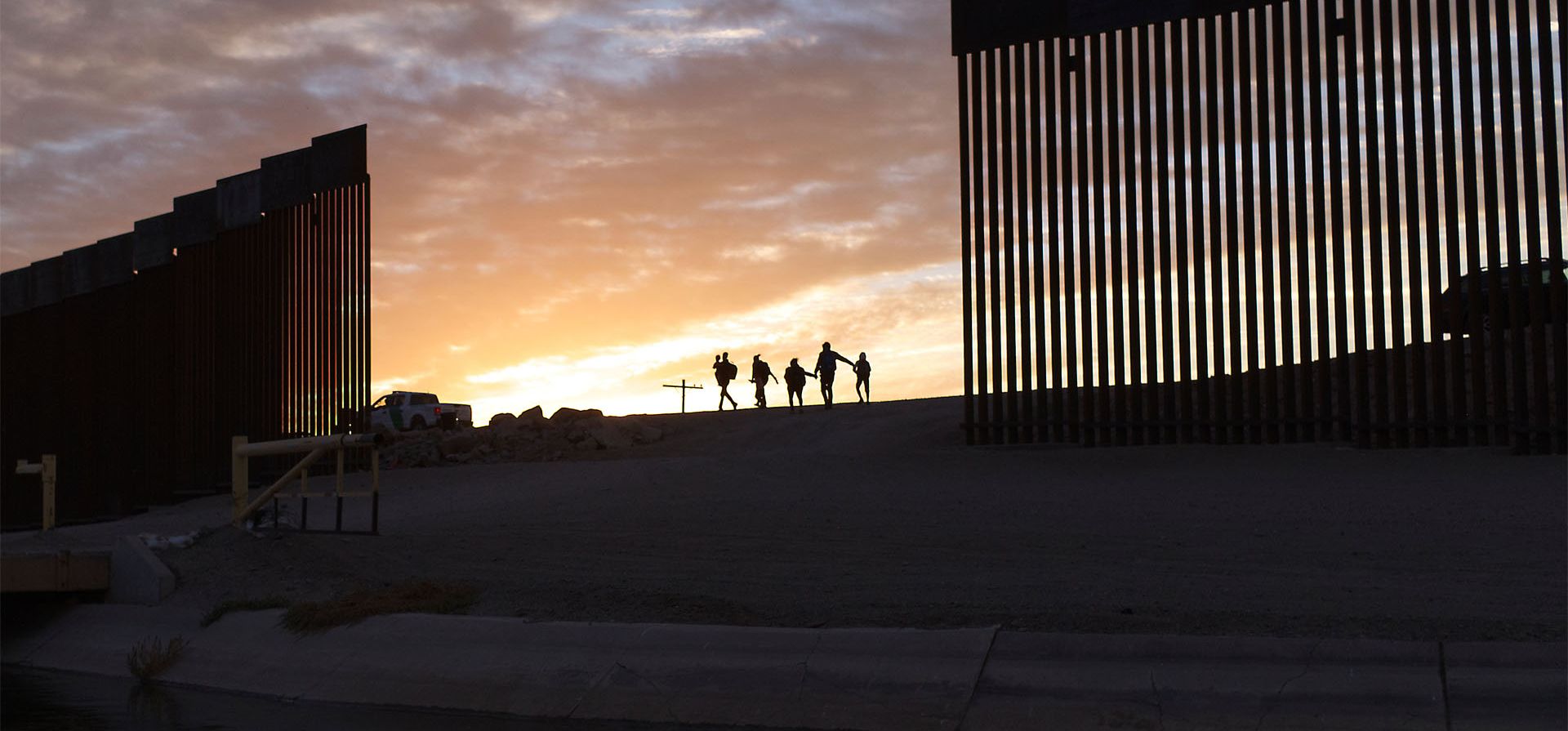 Una familia de migrantes atraviesan un hueco en el muro fronterizo para llegar a los Estados Unidos después de cruzar desde México en Yuma, Arizona, para buscar asilo. Las familias son parte de una afluencia de solicitantes de asilo, ingresando a los EE. UU. en el área de Yuma desde América del Sur.