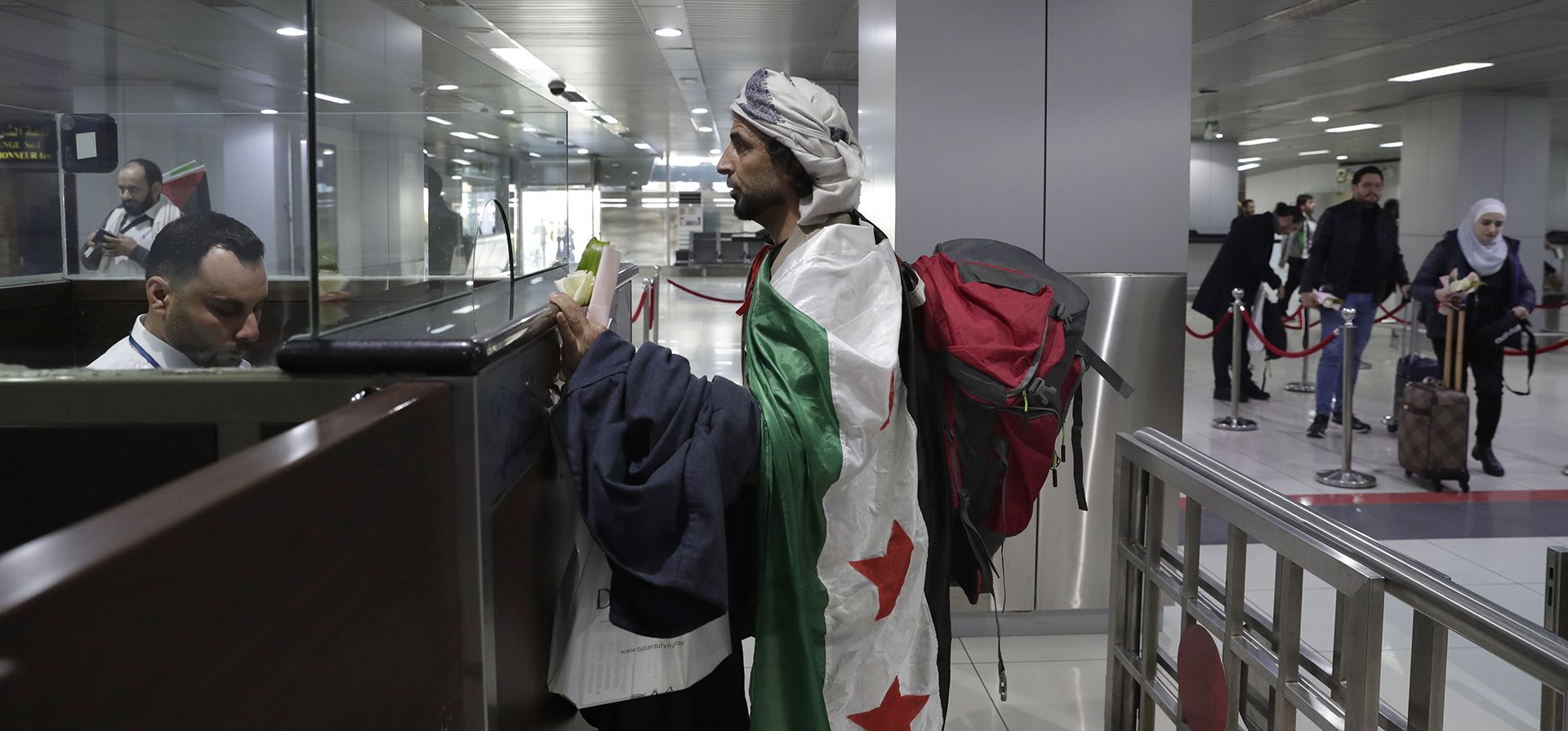 Un hombre que llegó en el primer vuelo comercial internacional desde la caída del expresidente sirio Bashar Assad se cubre con la bandera siria Un hombre que llegó en el primer vuelo comercial internacional desde la caída del expresidente sirio Bashar Assad se cubre con la bandera siria