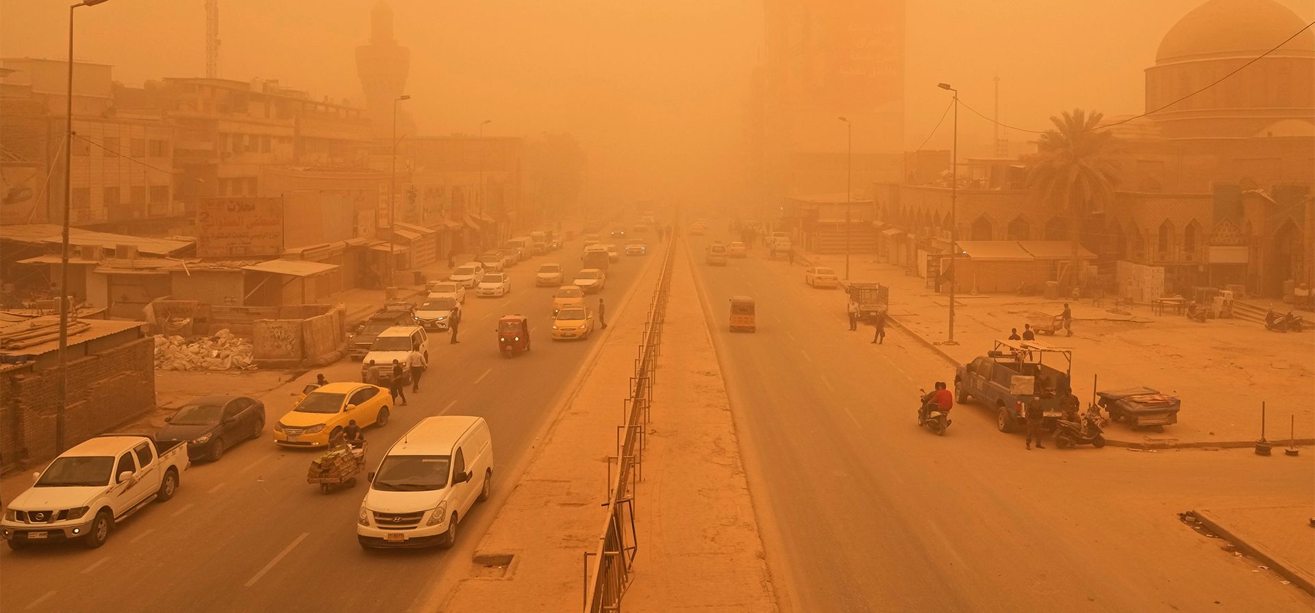 La gente camina por una calle durante una tormenta de arena en Bagdad, Irak, el lunes 16 de mayo de 2022. La tormenta de arena tiñó de ocre el cielo y cerraron aeropuertos y escuelas.