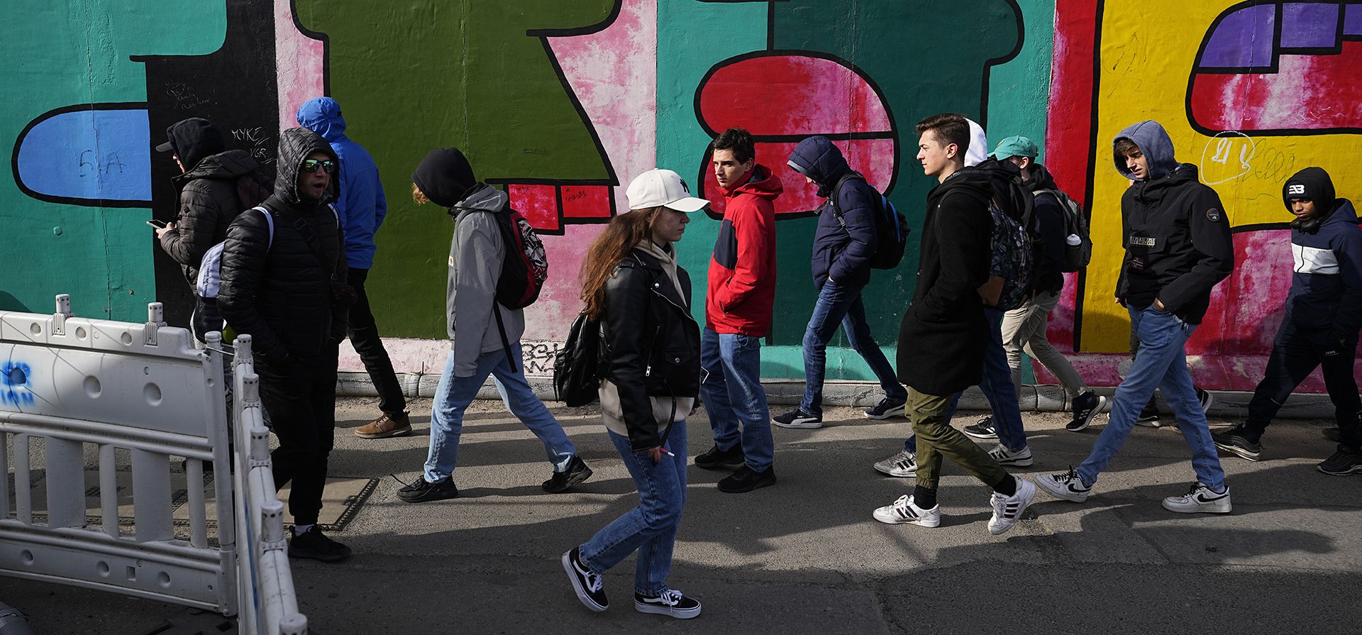La gente pasa frente al Muro de Berlín con las obras de arte