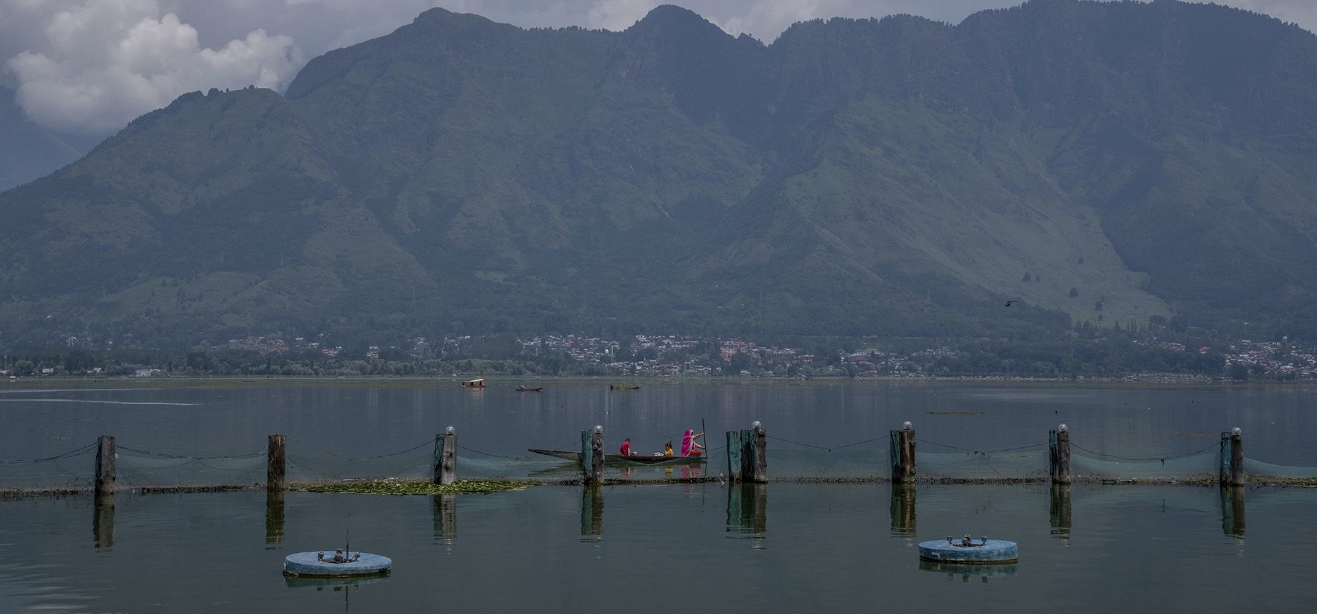 Una mujer de Cachemira junto con sus hijos reman su shikara en el camino de regreso a casa en las aguas del lago Dal en Srinagar, Cachemira controlada por India, el miércoles 27 de julio de 2022.