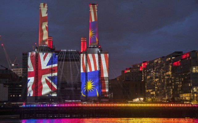 Las banderas nacionales se proyectan en la central eléctrica de Battersea, como parte de un espectáculo de luces para dar la bienvenida a los primeros residentes que se mudaron a la remodelación, en Londres.