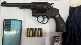 El arma plantada a la víctima y uno de los celulares sustraídos por los policías de la Brigada Motorizada en el operativo ilegal.