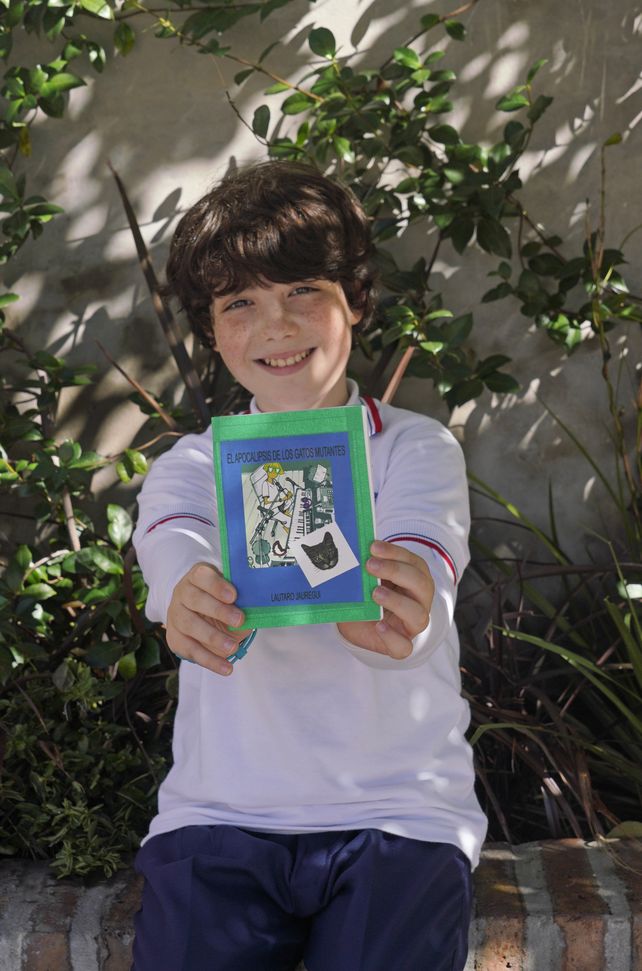 El estudiante muestra feliz el libro artesanal que se regaló su maestra.