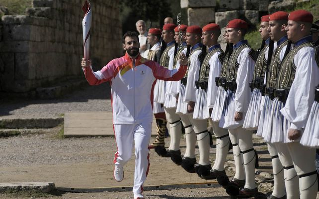 El primer corredor de esquí alpino griego Ioannis Antoniou pasa junto a los soldados de la Guardia Presidencial griega durante el encendido de la llama olímpica en el sitio de la Antigua Olimpia