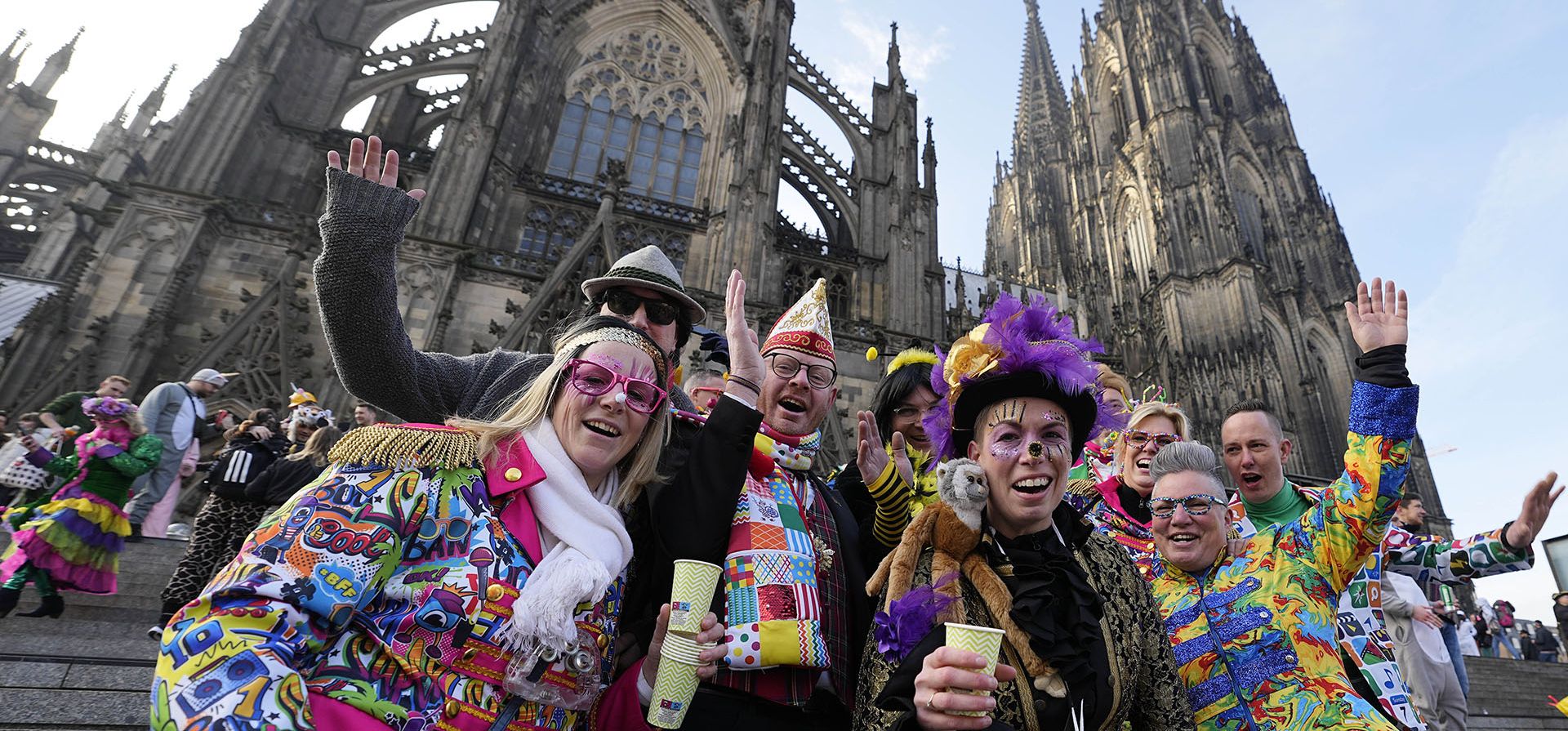 Un grupo de personas ataviadas con coloridos disfraces posan frente a la Catedral de Colonia al comienzo del carnaval callejero en Colonia, Alemania, el jueves 16 de febrero de 2023. (Foto AP/Martin Meissner)