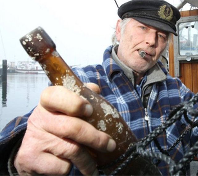 El pescador Konrad Fischer muestra su hallazgo de una botella con un mensaje lanzada al mar en 1913 (Foto :AFP)
