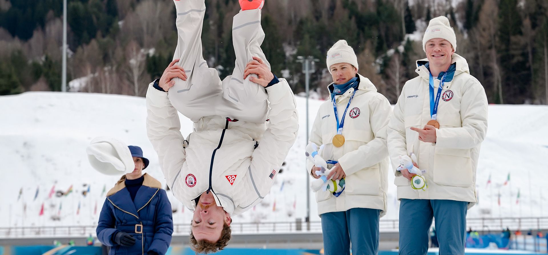 El medallista de plata Ben Ogden, de Estados Unidos, realiza una voltereta hacia atrás desde el podio mientras los medallistas de oro Johannes Hoesflot Klaebo, y el medallista de bronce Oskar Opstad Vike, ambos de Noruega, durante los Juegos Olímpicos de Invierno de 2026, en Tesero, Italia, el martes 10 de febrero de 2026. (Foto AP/Evgeniy Maloletka)