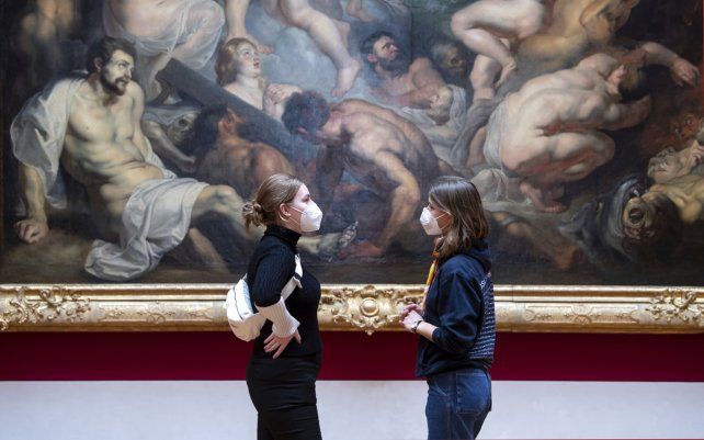 Visitantes se paran frente a la pintura