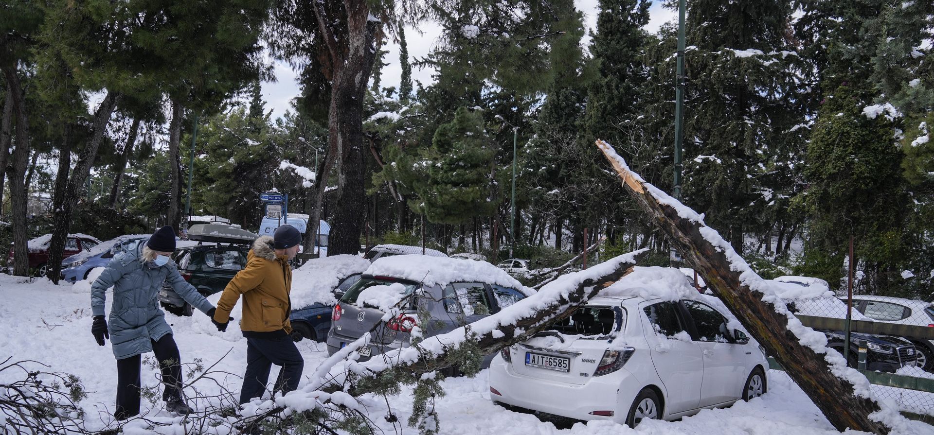 Una pareja pasa junto a un árbol caído en un vehículo estacionado, en Atenas, después de la tormenta de nieve. La caida intensa de nieve interrumpió el tráfico aéreo y por carretera el lunes en la capital griega de Atenas y la vecina ciudad más grande de Turquía. Estambul.