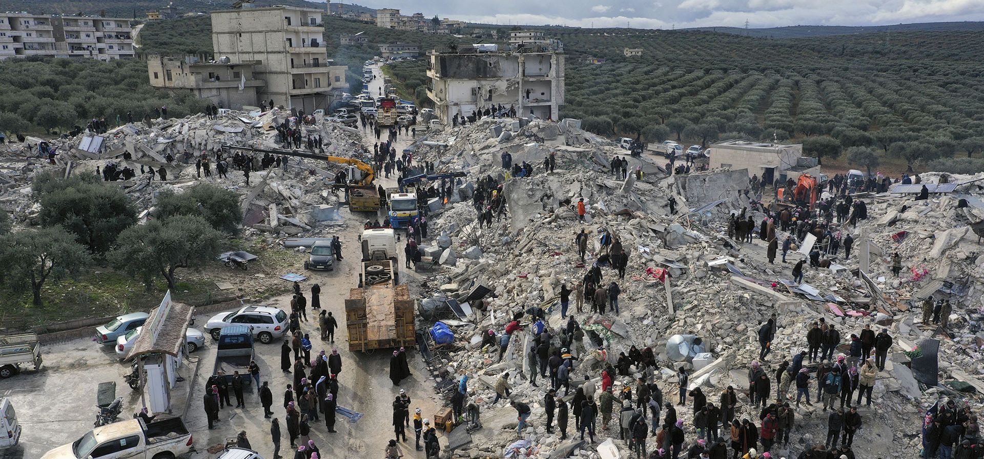 Trabajadores de defensa civil y residentes buscan entre los escombros de los edificios derrumbados en la ciudad de Harem, cerca de la frontera turca, provincia de Idlib, Siria. Un poderoso terremoto ha causado daños significativos en el sureste de Turquía y Siria. (Foto AP/Ghaith Alsayed)