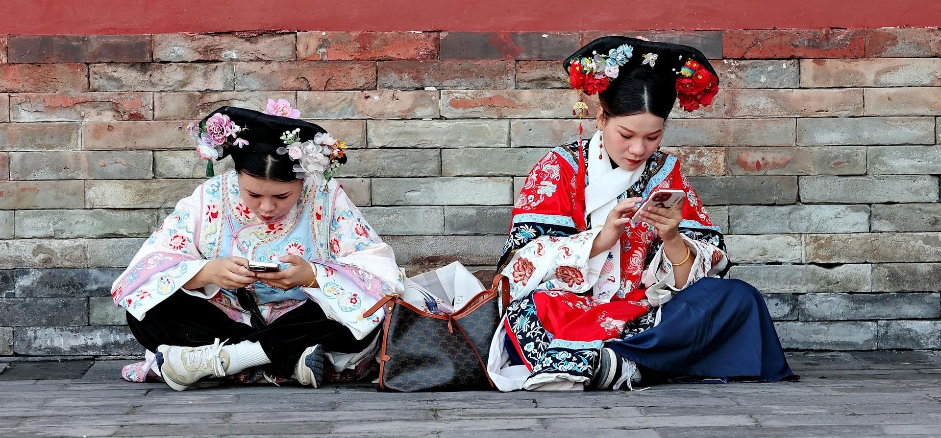 Dos mujeres jóvenes vestidas con trajes tradicionales revisan sus teléfonos en el parque Tiantan, Pekín, China. Fotografía: Rex/Shutterstock Dos mujeres jóvenes vestidas con trajes tradicionales revisan sus teléfonos en el parque Tiantan, Pekín, China. Fotografía: Rex/Shutterstock