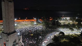 Elocuente. La manifestación en el Monumento contra las quemas y detrás, sobre las islas, un foco de incendio.