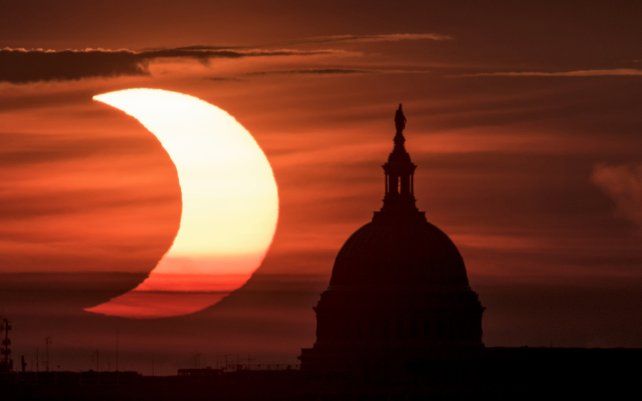 En esta foto proporcionada por la NASA, se ve un eclipse solar parcial cuando el sol sale a la izquierda del Capitolio de los Estados Unidos en Washington, visto desde Arlington, Virginia.