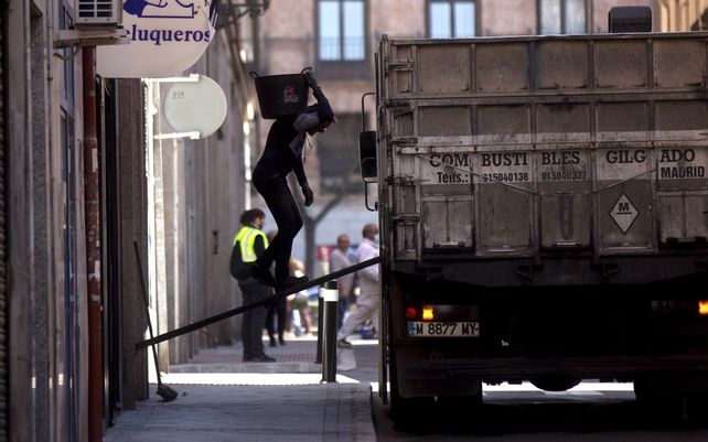 Un trabajador camina sobre una tabla hacia un camión mientras saca los residuos de escombros de un edificio en Madrid