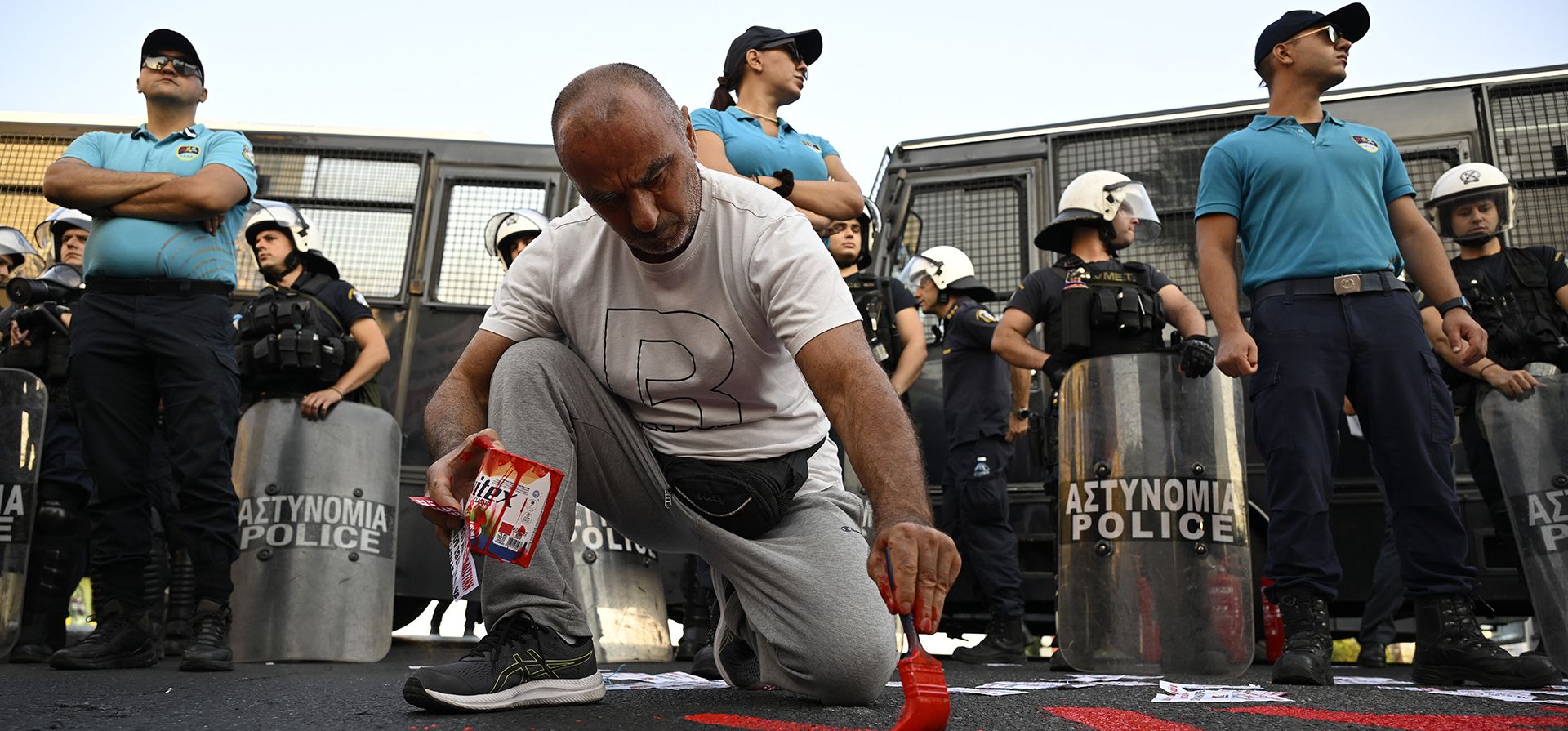 Un manifestante pinta una frase en el piso, frente a la policía, durante una protesta contra la llegada de un crucero con israelíes a bordo, en el puerto de Pireo, Grecia, el 14 de agosto de 2025. (AP Foto/Michael Varaklas) Un manifestante pinta una frase en el piso, frente a la policía, durante una protesta contra la llegada de un crucero con israelíes a bordo, en el puerto de Pireo, Grecia, el 14 de agosto de 2025. (AP Foto/Michael Varaklas)