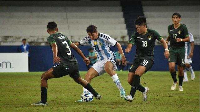 El juvenil rojinegro Valentino Acuña maniobra entre dos rivales bolivianos.