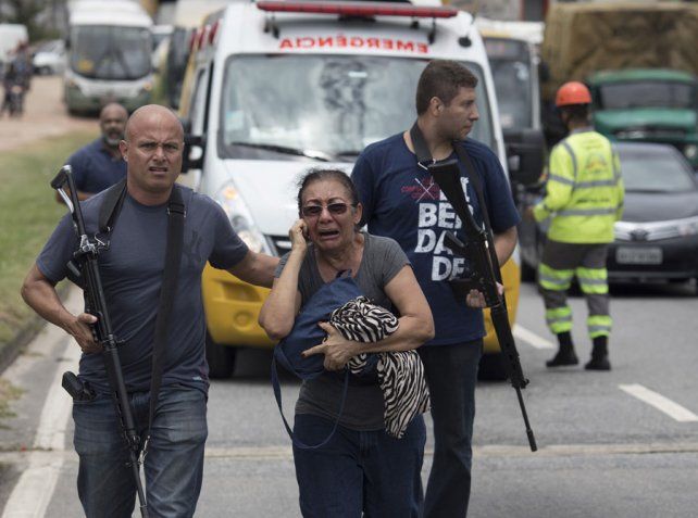 Operativos policiales. Fuerzas policiales con armas largas protegen a una mujer tras un violento tiroteo en Río de Janeiro. Foto: AP