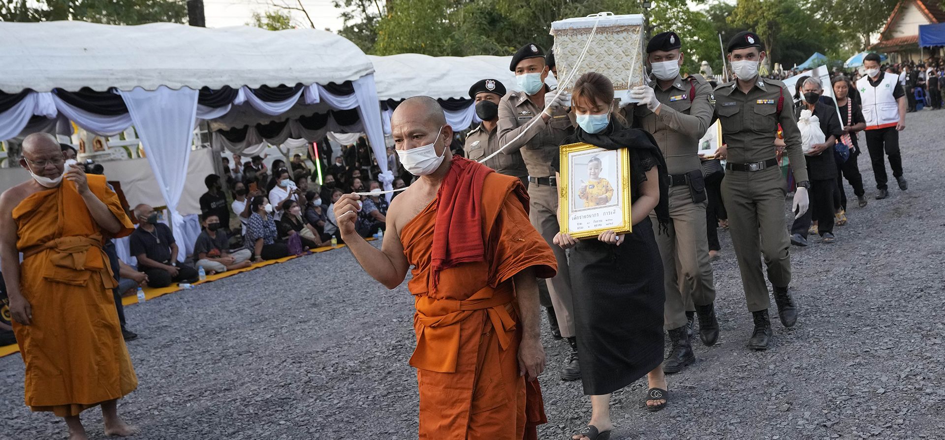Dirigida por un monje, la policía lleva un ataúd que contiene a una víctima en el ataque a la guardería para la cremación en el templo Wat Rat Samakee en Uthai Sawan, noreste de Tailandia, el martes 11 de octubre de 2022. Un exoficial de policía irrumpió en una guardería en el noreste de Tailandia el jueves pasado, matando a decenas de niños en edad preescolar y maestros.