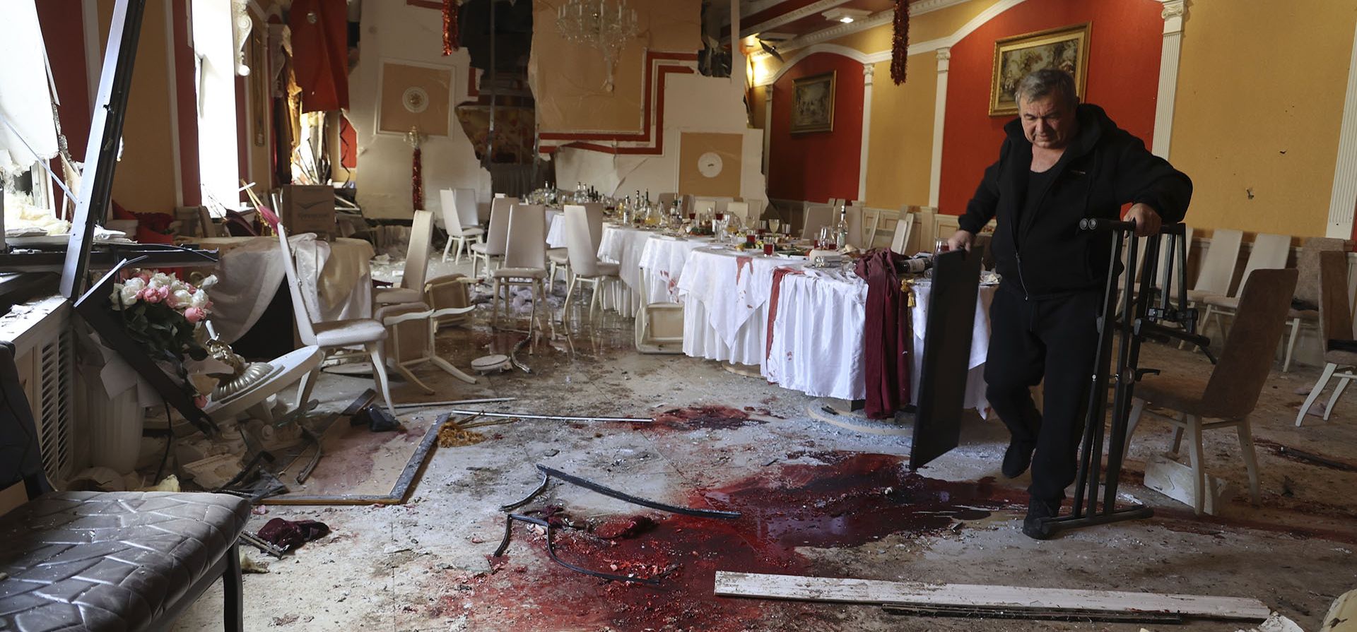 Un hombre camina junto a rastros de sangre en el suelo en un restaurante donde varias personas, incluido Dmitry Rogozin, el ex viceprimer ministro ruso y exjefe de la agencia espacial estatal Roscosmos, resultaron heridas el miércoles durante una reunión con funcionarios rusos en Donetsk por un bombardeo de las fuerzas ucranianas en Donetsk, la capital de la región de controlada por Rusia, el jueves 22 de diciembre de 2022. (Foto AP/Alexei Alexandrov)