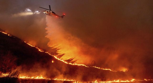 Un helicóptero lanza agua sobre el incendio Kenneth en la sección West Hills de Los Ángeles.