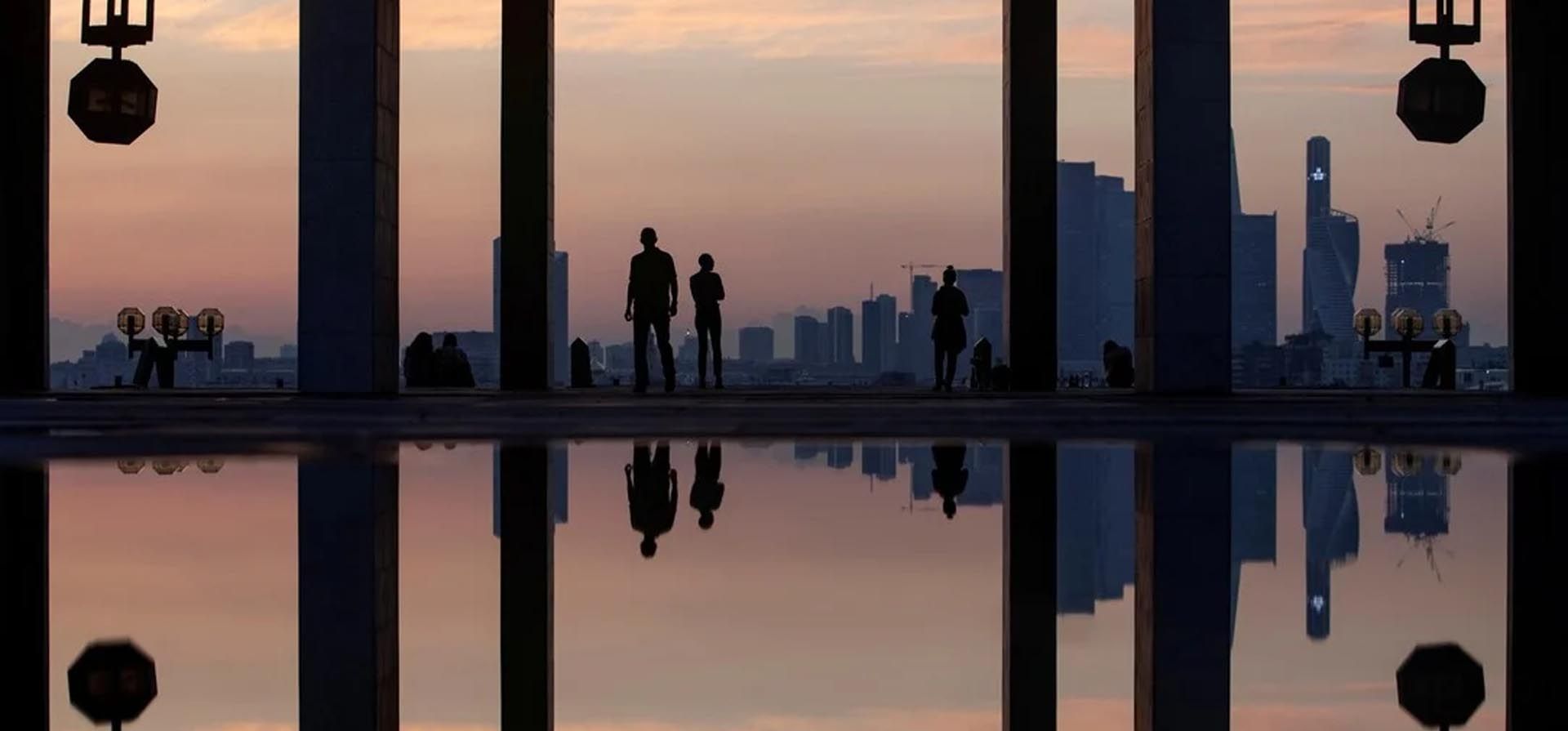Las personas se reflejan en un charco mientras ven la puesta de sol en Moscú, Rusia, el 27 de mayo de 2021. Foto: Reuters