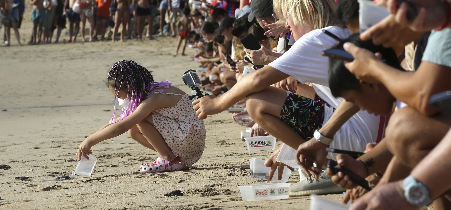 Turistas hacen fila mientras liberan tortugas bebés en el océano en la playa de Kuta, Bali, Indonesia, el miércoles 17 de agosto de 2022. Unas cuatrocientas tortugas Lekang recién nacidas fueron liberadas durante una campaña para salvar a las tortugas marinas en peligro de extinción.