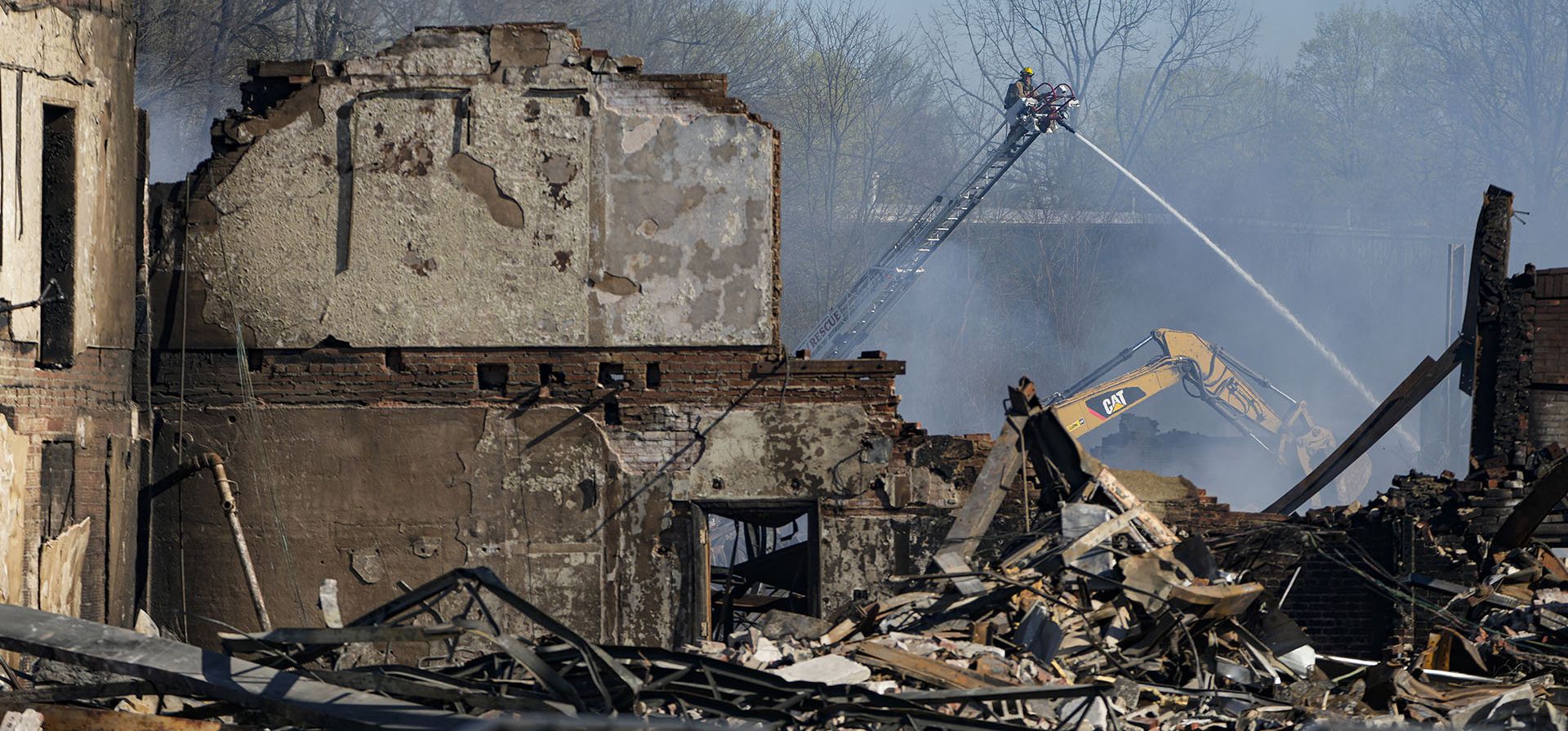 Bomberos y trabajadores recogen los escombros de un incendio industrial que continuaba ardiendo en Richmond, Indiana, el jueves 13 de abril de 2023. Múltiples incendios que comenzaron a arder el martes por la tarde todavía ardían dentro de unos 14 acres de varios tipos de plásticos almacenados dentro y fuera edificios en el sitio de la antigua fábrica. (Foto AP/Michael Conroy)