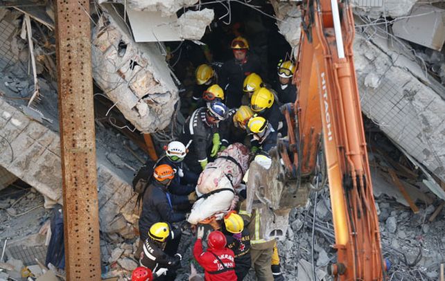 Penoso. Bomberos trasladan un cuerpo de uno de los edificios colapsados por el sismo en Tainan